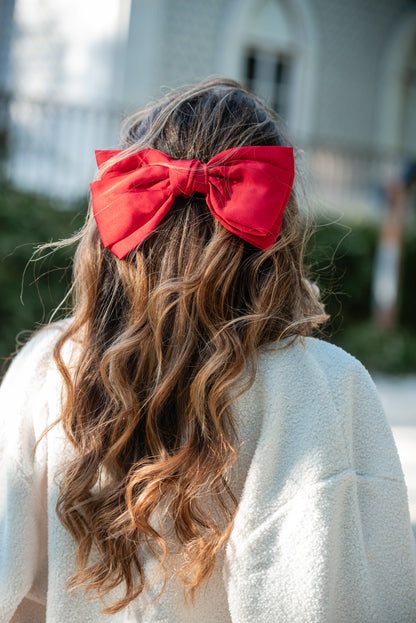 Carmo de costas com o gancho-laço vermelho em cetim no cabelo