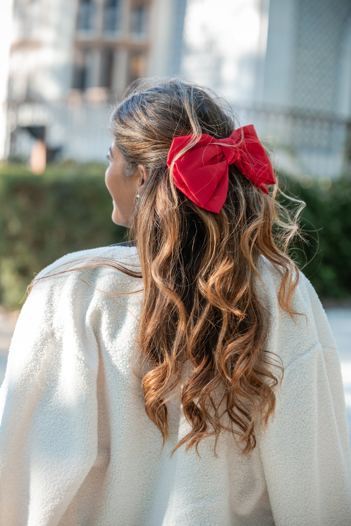 Gancho-laço vermelho em cetim no cabelo, visto de lado