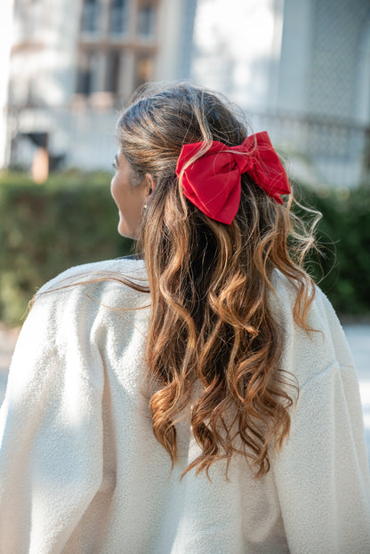 Gancho-laço vermelho em cetim no cabelo, visto de lado