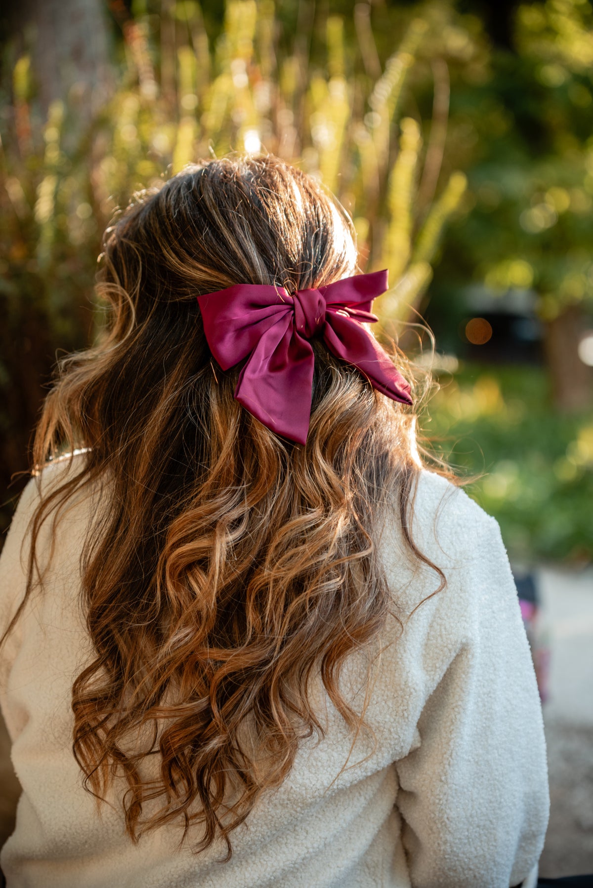 Carmo de costas com o gancho-laço framboesa em cetim no cabelo