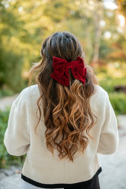 Carmo de costas com o gancho-laço vermelho em veludo no cabelo